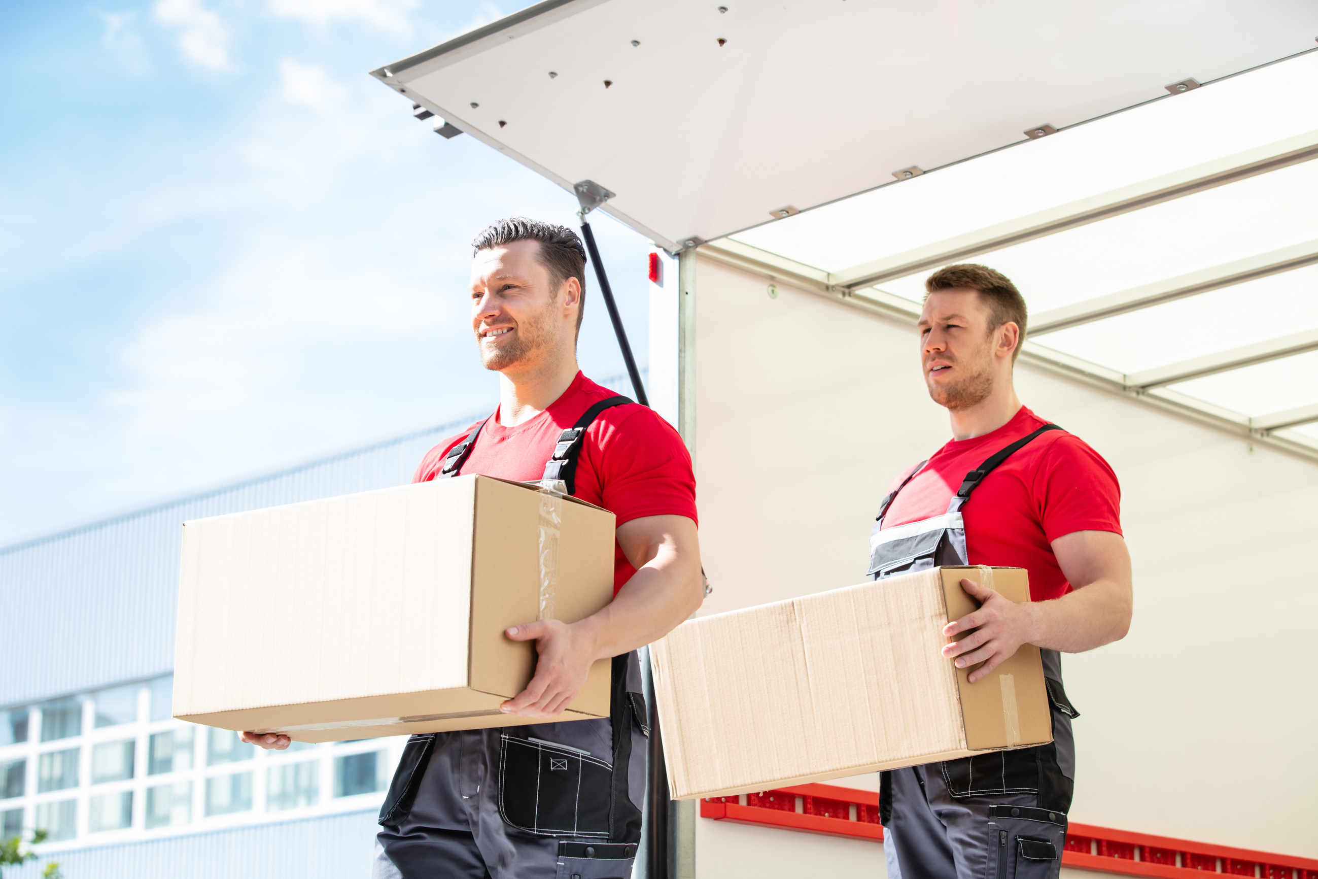 Happy Male Movers Holding Cardboard Boxes